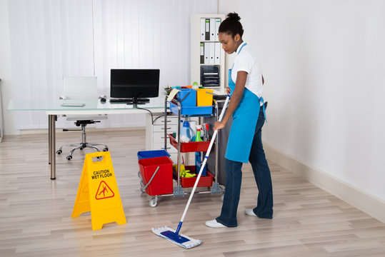 Female Janitor Mopping Floor In Office