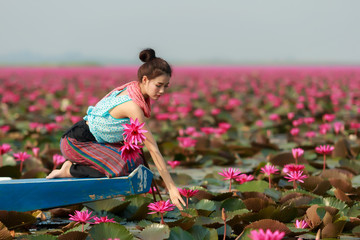 Beautiful girl sitting in boat in the lotus field