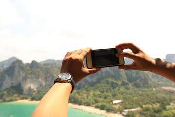 hiker hands taking photo with smartphone at seaside