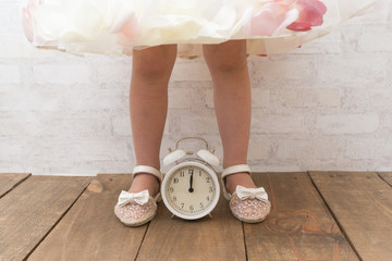 ドレスを着た女の子の足と目覚まし時計