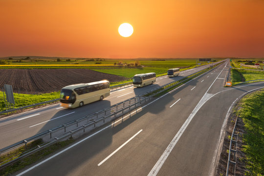 Fast travel buses in a row on the highway at sunset