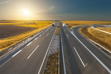 Two lone trucks on the empty highway at sunset