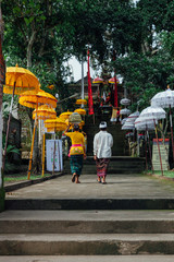 Balinese woman with man going to the temple with ceremonial box on her head during Balinese New Year or Nyepi Day celebrations on in Ubud, Bali