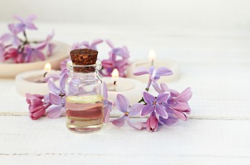 Obraz na płótnie Canvas Essential oil in bottle, lilac flowers, tea-candles. Soft focus.