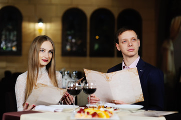 guy with a girl in a restaurant choose dishes from the menu