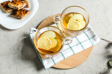 Cup of green tea with cinnamon, lemon and apples