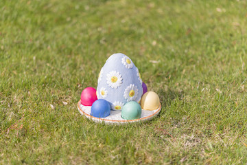 Bunte Ostereier mit einem großen Porzellanei auf gemähtem grünen Gras im Garten