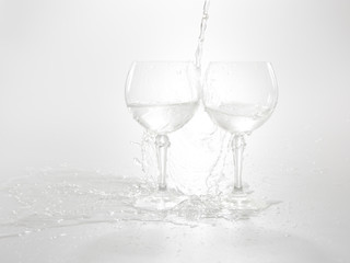 Water is pouring in two wine glasses