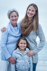 Three generations of women standing at beach