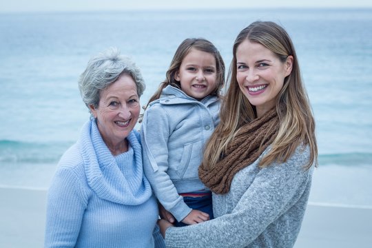 Happy three generations of women standing at beach