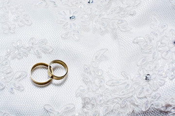 Two wedding rings laying on wedding dress