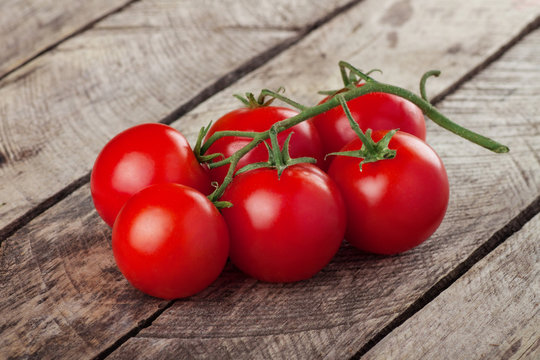 branch of cherry tomatoes on wooden background