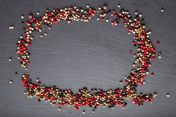 pepper scattered on slate, top view, a place for an inscription