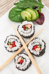 Close up image of uramaki sushi rolls covered with black sesame seeds.