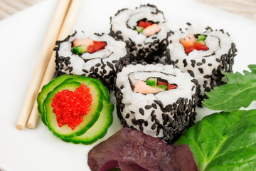 Close up image of uramaki sushi rolls covered with black sesame seeds.