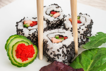 Close up image of uramaki sushi rolls covered with black sesame seeds.