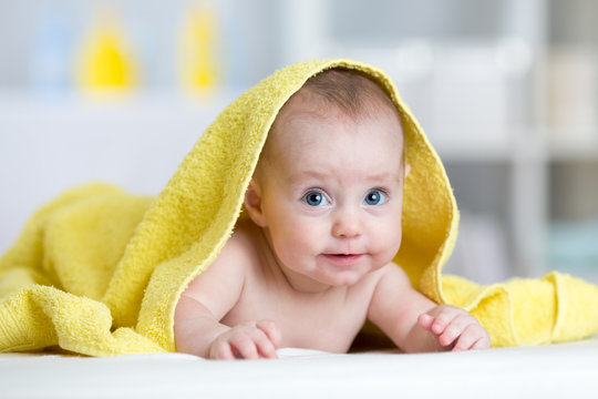 Smiling baby after shower or bath with towel on head