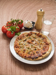Pizza and some ingredients on a wooden table.