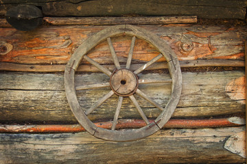 Obraz premium Old carriage wheel on old wood wall