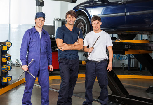 Confident Mechanics Holding Worktools At Garage