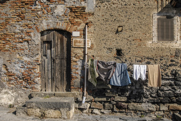 Casa in mattoni e pietre con vestiti appesi, vintage, paese della sicilia, italia antica.