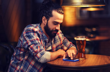 man with smartphone and beer texting at bar
