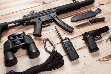 Obraz premium Assault rifle, gun, knife with sheath, compass and notebook with pen on table.