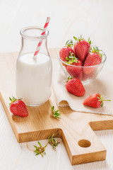 Milk and strawberry on white wooden background