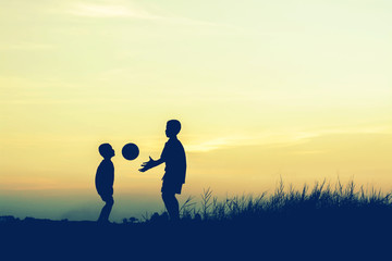 boys playing football at sunset. silhouette concept