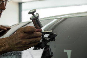 A man using repairing equipment to fix damaged windshield