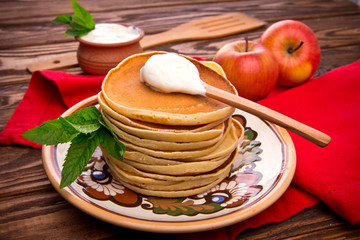 Stack of pancakes with mint and sour cream