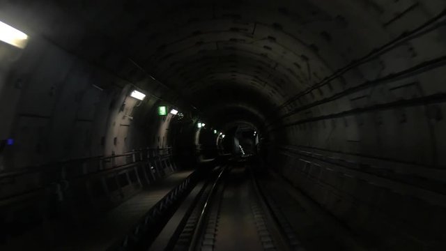Slow motion shot from the subway train drivers cabin, train is moving in the subway tunnel and arriving to the station.