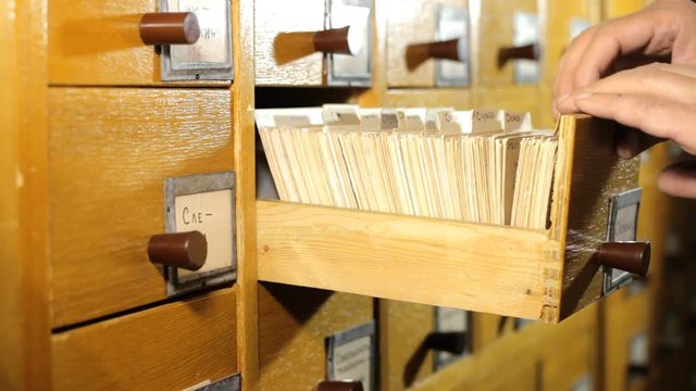 Man looking for a book in the library card catalog