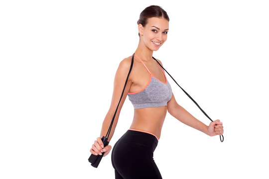 Skipping offers great cardio! Pretty young  woman holding a skipping rope around her neck against a white isolated background.