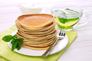 Stack of pancakes with mint and sour cream