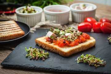 Grilled toasted bread with roasted tomatoes, feta cheese and radish sprouts.