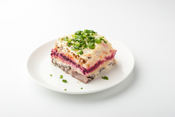 Herring under beetroot and mayonnaise in a white ceramic plate