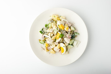 Olivier salad in ceramic plate on white background