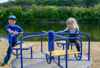 Two laughing children playing on a merry-go-round