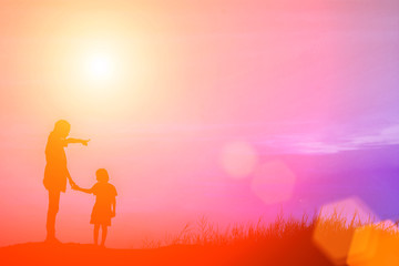 Mother encouraged her son outdoors at sunset, silhouette concept