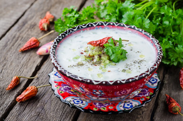 Tzatziki or cacik, cold cucumber and yogurt soup or salad with mint leaves on wooden background. Selective focus
