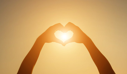 Silhouette hand heart shape with sun light