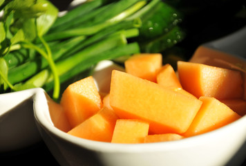 Pieces of pumpkin on a white plate with greens