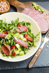 Arugula salad with salami, onions and tomatoes