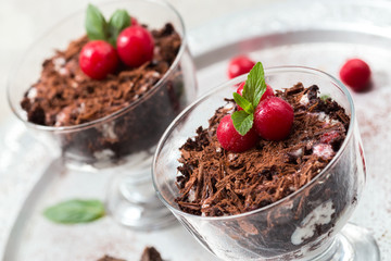 Chocolate desserts with whipped cream and cherries in glasses,light grey background, selective focus, close up