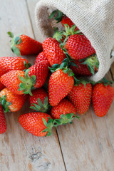 strawberries in small sack on wooden table background