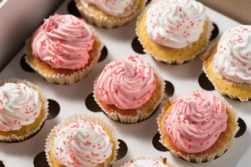 Cupcake packaging, delivery box, vanilla cupcakes with pink and white cream,top view, selective focus, close up
