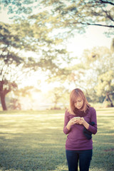 Woman standing in park writing text on smartphone