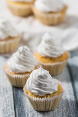 Vanilla cupcakes with white cream on wooden table, whipped cream, selective focus