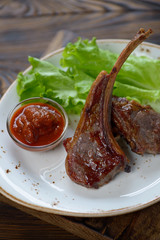 Roasted lamb chops with fresh green salad and dip sauce, closeup